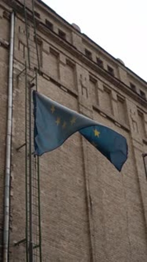 EU Flag Waving Beside Building's Fire Escape Ladder