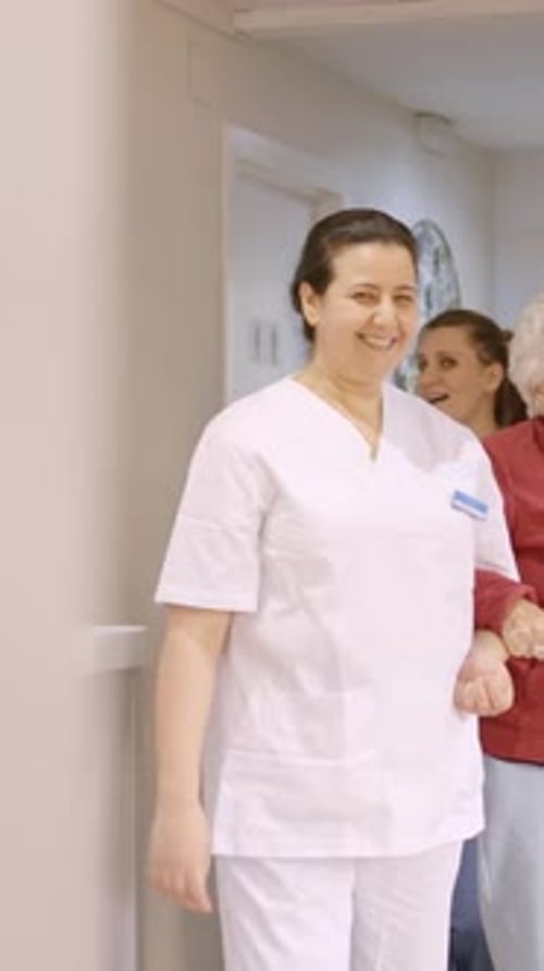Medical Professional Helping Senior Woman Walk in Hallway