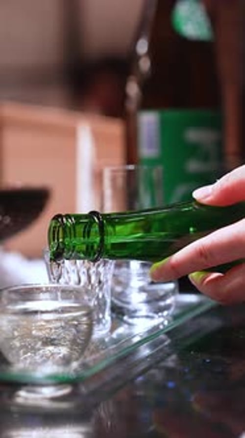 Close Up Pour of Clear Liquor Into Small Cups on Glass Tray