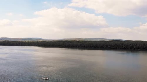 Slow motion 4k video of sunny day on the Danube river with fishing boat and beautiful clouds on the