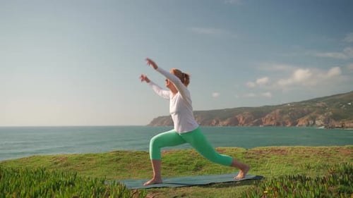 Fit Mature Woman in Warrior Pose Practicing Yoga Near Sea