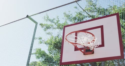 Fliegender Ball auf einem sonnigen Basketballplatz, in Zeitlupe