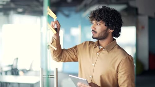 Young creative entrepreneur business man in office uses post papers sticky notes to share idea.