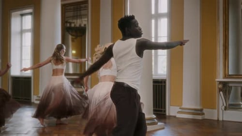 Dancers practicing modern dance moves in large hall