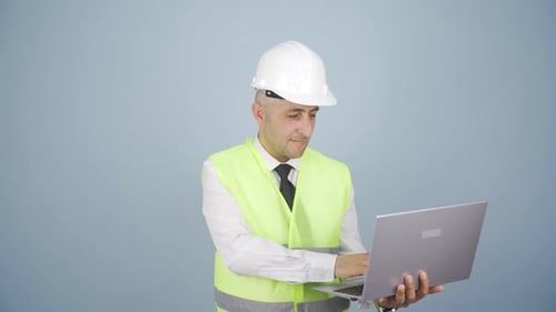 Engineer holding laptop laughing at camera.