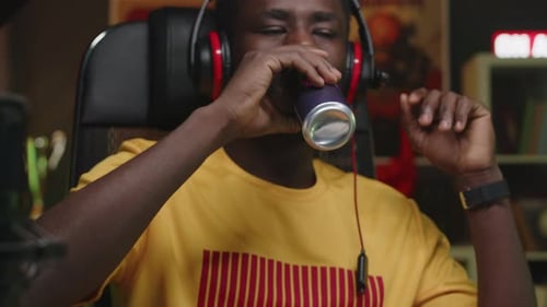 Young Black Male Gamer Drinking Energy Drink from Can while Playing at Home