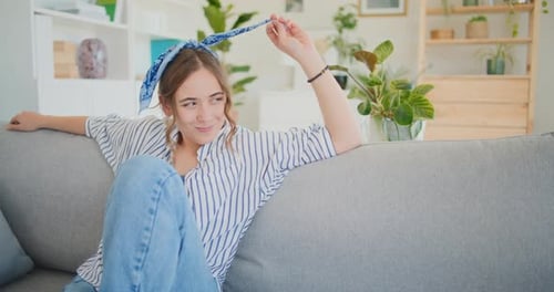 Woman Smiling on Gray Sofa in Bright Living Room