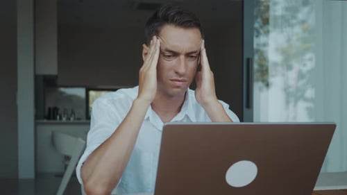 Stress and Headache Overwhelm Tired Businessman Working on Laptop at Home Office Exhausted Man