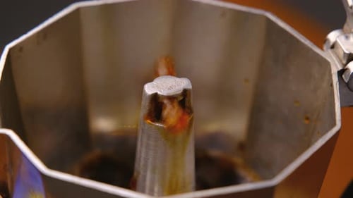 Hot coffee is boiling and steam comes out of a moka pot, close-up.