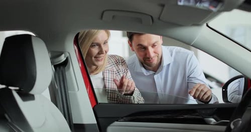 Attractive Young Couple Discussing Chosen Auto in Automobile Showroom Concept of Car Shopping Buying