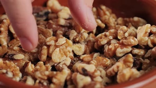 Close Up of Walnuts in Bowl With Fingers