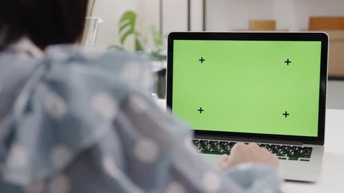 Dolly shot over the Shoulder : Young Woman Sitting at Her Desk Using Laptop with Green Screen.