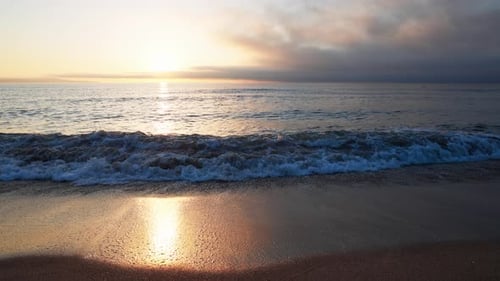 Black Sea and Beach Nearby Against a Sky with Clouds and a Dawn Sun