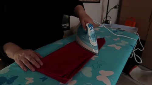 Woman is ironing at home on ironing board