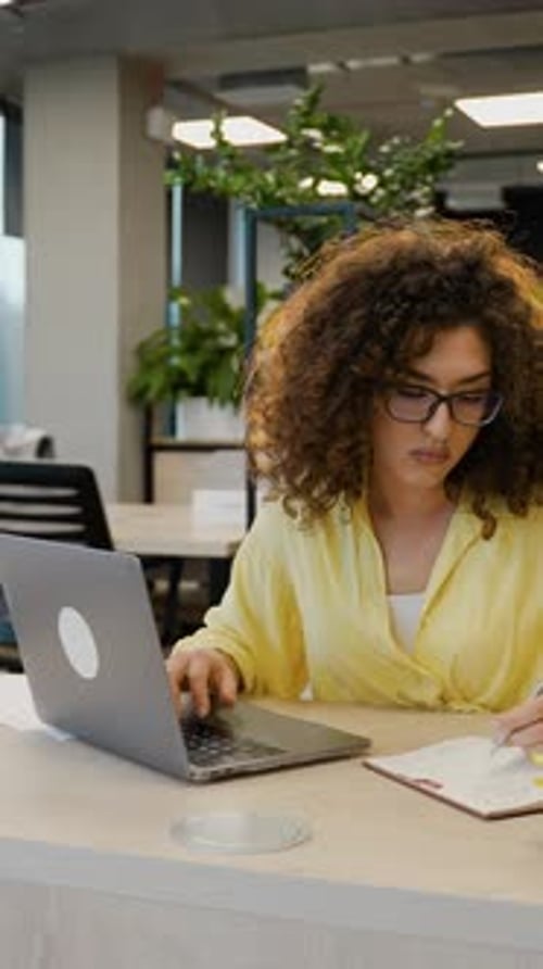 Woman Works on Laptop, Takes Notes at Desk
