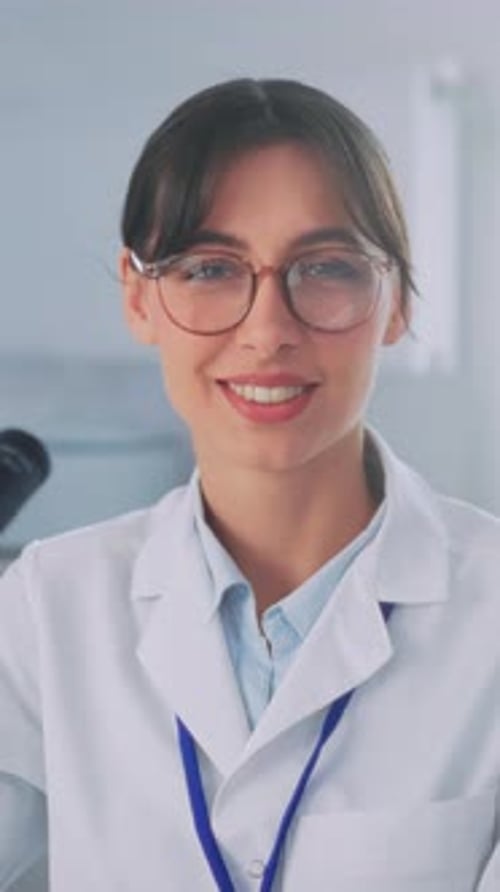 Woman Scientist Looks at Microscope and Smiles