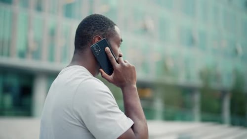 Portrait of Man Talking on the Phone on the Street African American Man is Calling on a Smartphone