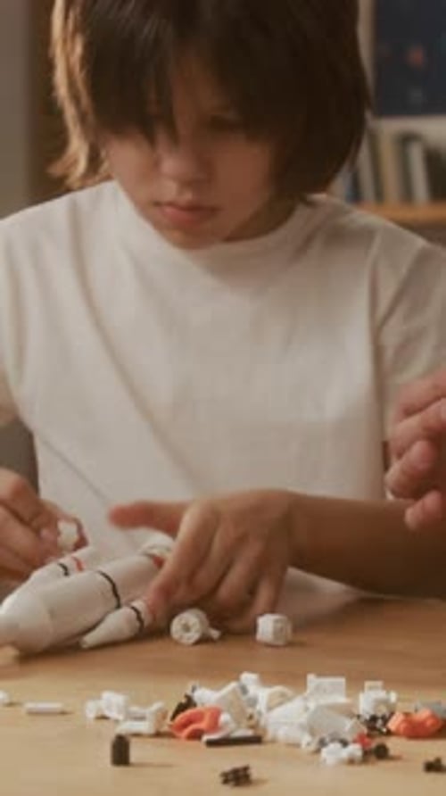 Vertical de un niño con su padre ensamblando un cohete espacial de juguete para aprender STEM