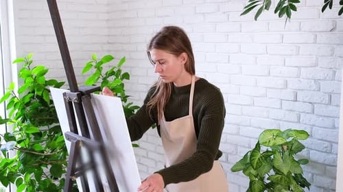 Beautiful female artist painting picture in art studio.