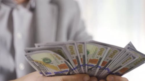 Close-up businessman counting dollars.
