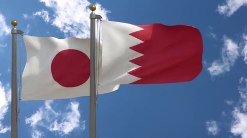Japan and Bahrain Flags Waving Together Against Blue Sky
