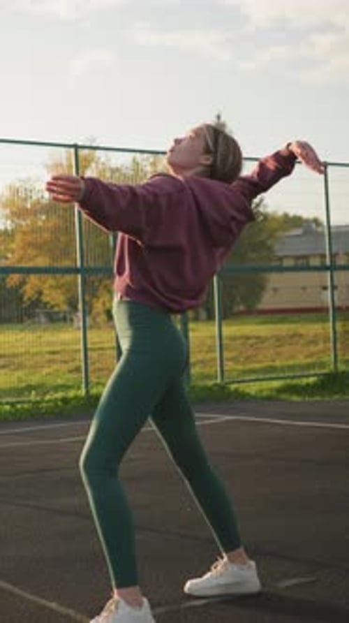 Athletic Woman Serves Volleyball on Outdoor Court with Open Field Background