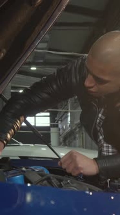 Dedicated Young Man Passionately Repairing His Car in a Welllit Garage