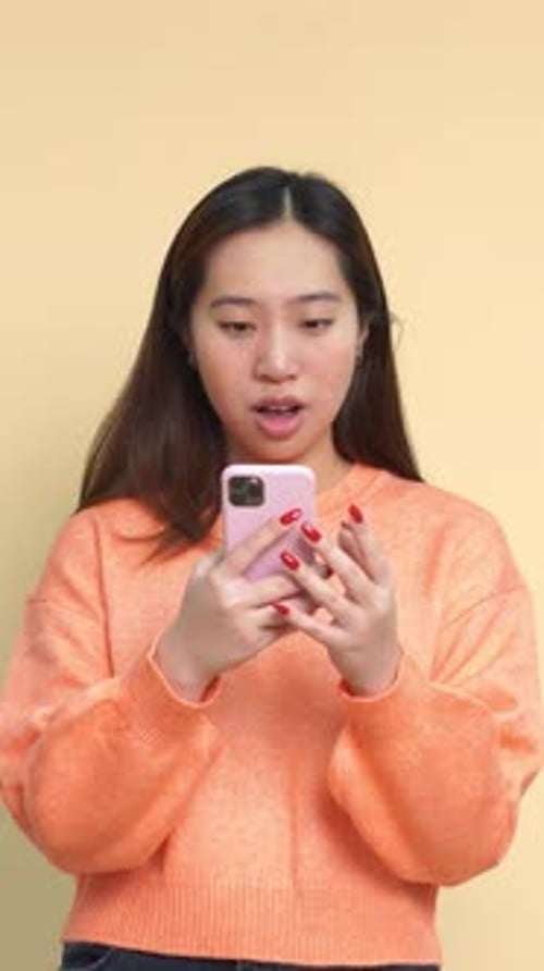 Young Woman Looks at Mobile Phone