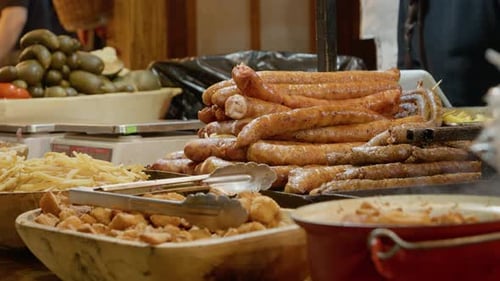 Steaming sausages and fried potatoes at a street food stall