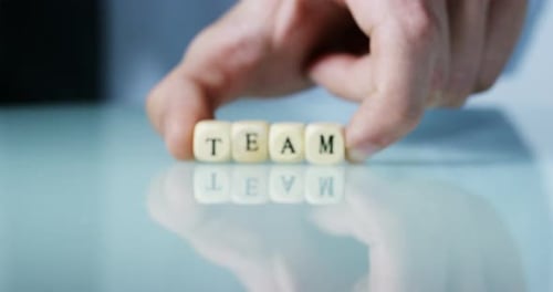 Der
junge Geschäftsmann hält das Wort „Team“ auf den hölzernen Buchstabenblöcken in der Hand. Konzept des Finanzmarktes