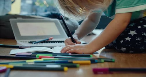 Niña dibujando con lápiz de color en el piso de la sala de estar el fin de semana