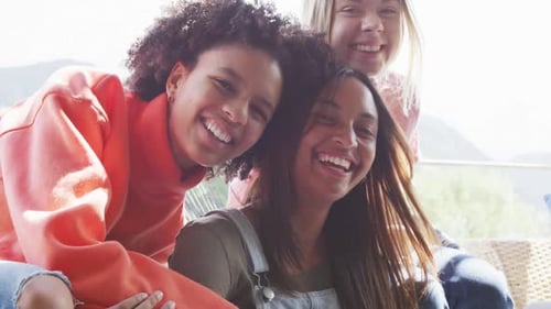 Retrato de amigas adolescentes felizes e diversificadas se abraçando em casa, em câmera lenta