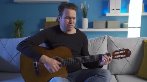 Man Plays Guitar on Couch in Living Room