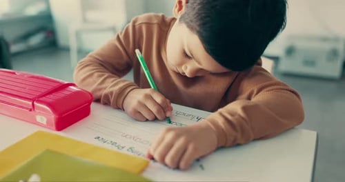 Boy Practices Writing at Table