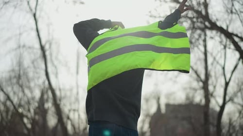 Man Outdoors Putting on Bright Neon Green Reflective Safety Vest