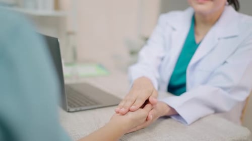 Doctor Comforting Patient by Holding Hands