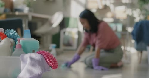 Young Woman Scrubbing Floor Disinfecting with Detergent While Bucket of Cleaning Products Visible on