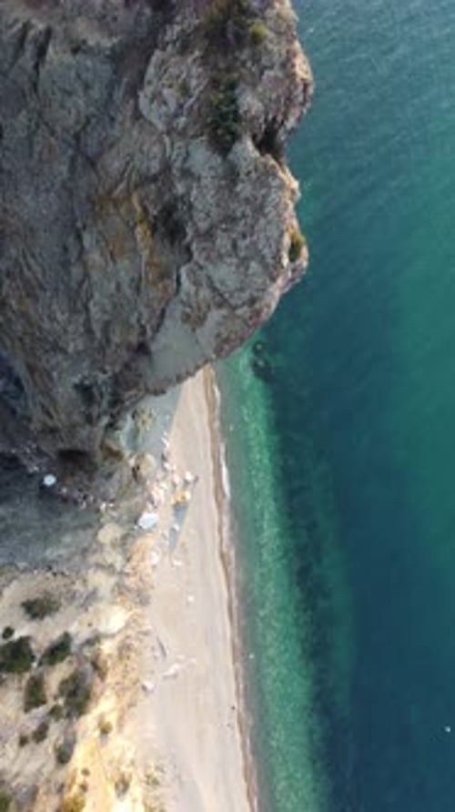 Aerial Vertical View of Beach with Wave Caressing Shore Sun Glare Small Waves on the Water Surface
