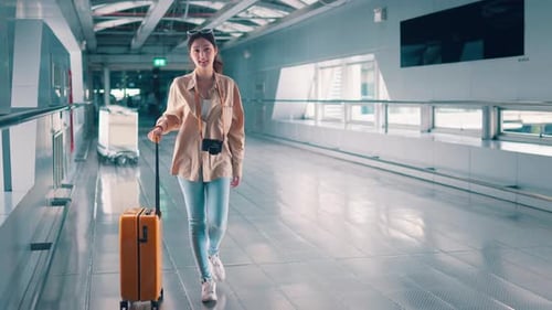 Happiness smiling asian woman passenger walking with a yellow suitcase luggage at airport terminal