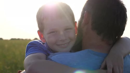 Affectionate Child Hugging a Man in Sunlit Field