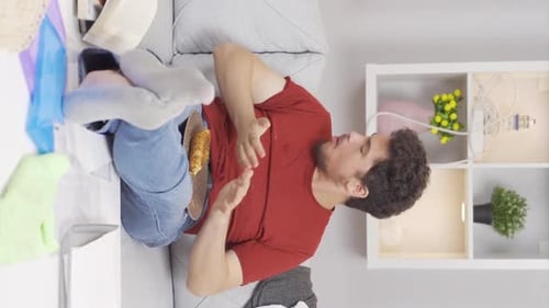 Man Eating on Couch in Messy Apartment