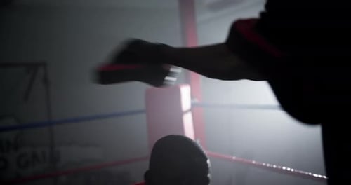 Man Boxing with Trainer in Dark Gym