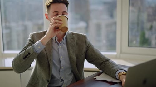 Happy Manager Drinking Coffee at Office Work on Modern Workplace with Big City on Background