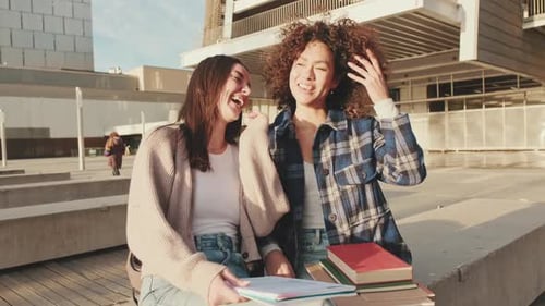 Garotas compartilham novidades e se divertem sentadas ao lado da universidade