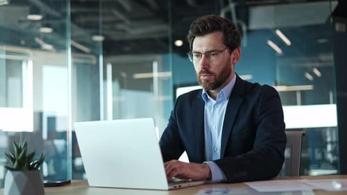 Focused Man Works on Laptop in Modern Office