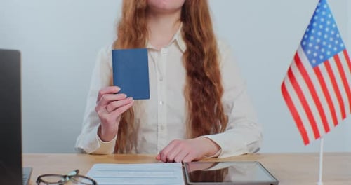Woman Holding Passport Near American Flag Indoors
