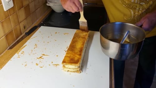 Close-up of a man brushing apricot glaze onto a large Mille-Feuille dessert