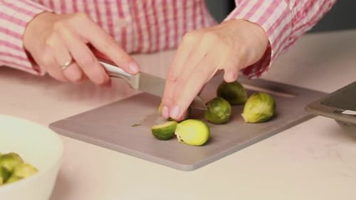 A Woman Cuts Brussels Sprouts in the Kitchen The Process of Cooking Vegetable