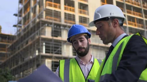 Construction Workers Discussing Blueprints at Construction Site