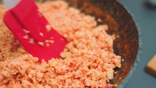 Orange Food Mixture Stirred in Cast Iron Pan